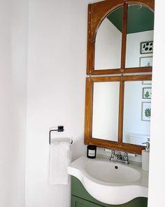 An antique mirror with two separate sections is held together by small hooks and displayed above a forest-green vanity. The green paint provides a refreshing look to the vanity and uses earth tones to add a natural feel to a white background. The curvature of the white sink softens the bunt edges on the rest of the decor...   Image: thebeckerhouse__