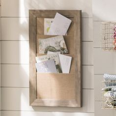 there is a wooden frame with some books on it and two wire baskets hanging from the wall