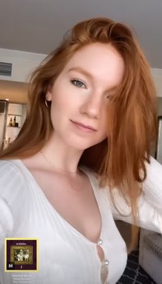 a woman with long red hair is taking a selfie in the mirror while wearing a white shirt