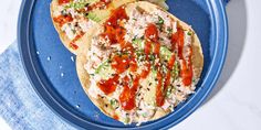 two pieces of bread with meat and vegetables on it sitting on a blue plate next to a fork