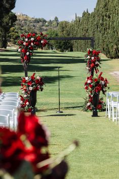 rows of white chairs with red flowers and greenery in the back ground at a wedding ceremony