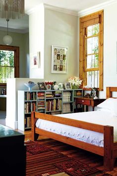 a bedroom with a bed, bookshelf and pictures on the wall above it