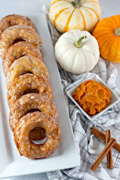 a plate with donuts on it next to small bowls of dips and pumpkins