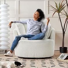 a woman is sitting in a chair with her two dogs on the floor next to her