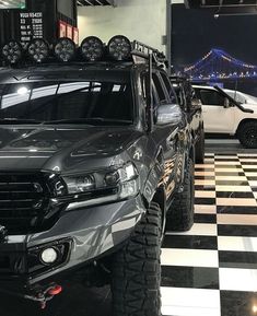 two trucks are parked in a garage with black and white checkered flooring