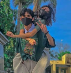 two people wearing face masks are walking down the street with their arms around each other