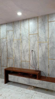 a room with marble walls and a wooden bench in front of the wall that has wires on it