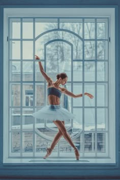 a ballerina is standing in front of a window