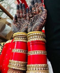 two hands with henna tattoos and bracelets on them