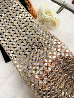 a gold sequined purse sitting on top of a white table next to flowers