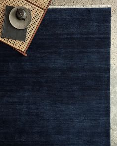 a blue rug on the floor next to a coffee table with a lamp and other items