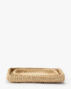 a woven tray with handles on a white background, it is made from jute and has been placed in the shape of a rectangular basket