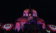 people standing in front of a building with lights on it