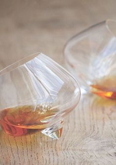 two glasses filled with liquid sitting on top of a wooden table next to each other