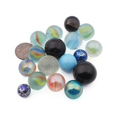 a pile of glass marbles sitting on top of a white table next to a penny