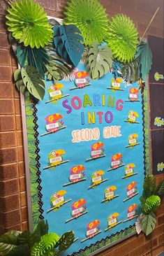 a bulletin board that says soaring into second grade with green leaves on it