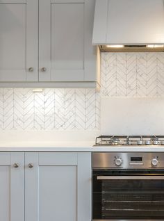 a stove top oven sitting inside of a kitchen next to white cupboards and drawers