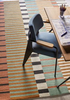 a chair sitting on top of a colorful rug next to a table with pens and pencils