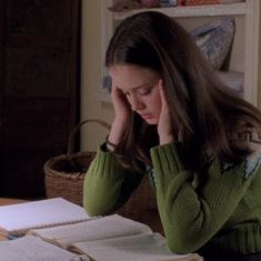 a woman sitting at a table with papers in front of her and looking down on her head