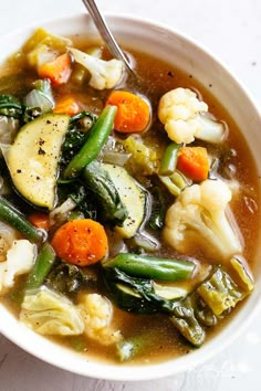 a white bowl filled with vegetable soup on top of a table