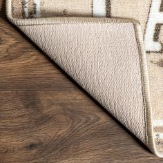 an area rug on top of a wooden floor with a brown and white design in the middle