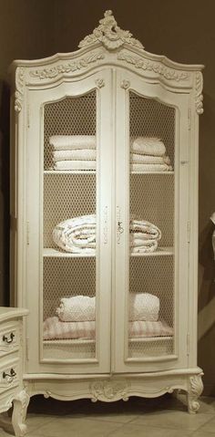 an antique white armoire with glass doors