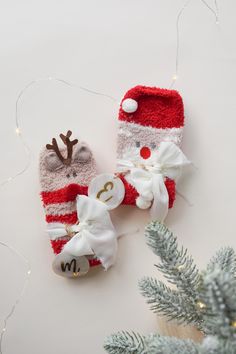 two knitted christmas mittens with reindeer noses and bows