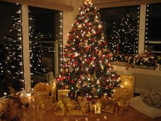 a decorated christmas tree in a living room next to a window with lights on it