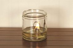 a lit candle in a glass jar on a wooden table