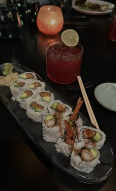 sushi on a plate with chopsticks and a drink