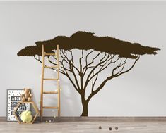 a tree with no leaves on it next to a ladder and wall decal in a room