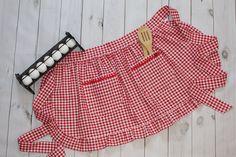 a red and white gingham shirt with a wooden spoon on it next to some candles