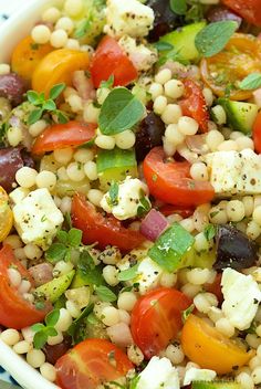 a salad with tomatoes, corn and feta cheese in a bowl on a table