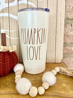 a white cup sitting on top of a wooden table next to a knitted pumpkin