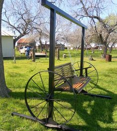 a wooden bench sitting on top of a lush green field next to a metal pole