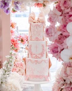 a three tiered cake with pink flowers around it