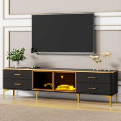 an entertainment center with a flat screen tv mounted on the wall and gold trimmings