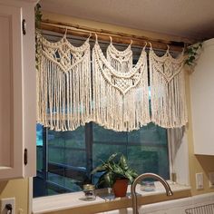 a kitchen window with macrame curtains hanging from it's side