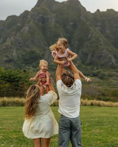 three people holding two small children in the air