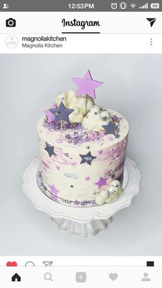 a white cake with purple stars on top and pink frosting is sitting on a plate