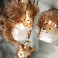 two christmas ornaments are hanging from strings with fur on them and one is wearing a furry hat