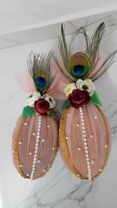 two pink vases with flowers and peacock feathers on top of a marble countertop