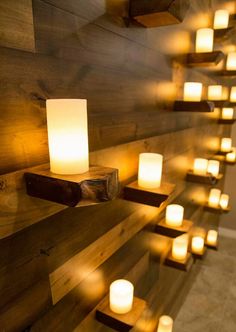 many lit candles are placed on the wall next to some wood planks and lights