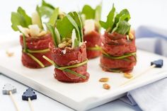 small appetizers with meat and veggies are arranged on a white plate