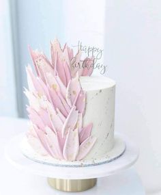 a white and pink cake with feathers on it