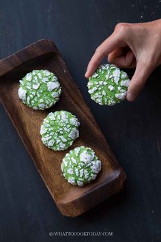 green cookies with white powdered sugar on a wooden tray