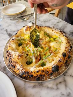 a person is cutting into a quiche with broccoli