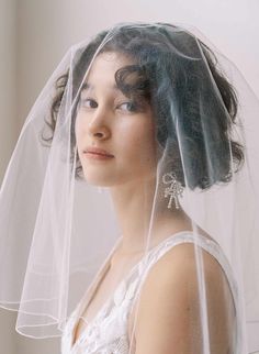 a woman wearing a veil and dress with her hair in the air, looking off to the side