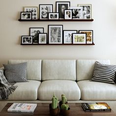 a living room filled with white furniture and pictures on the wall above it's coffee table