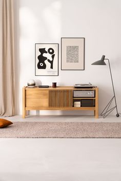 a living room with white walls and wooden furniture in the corner, along with two framed pictures on the wall